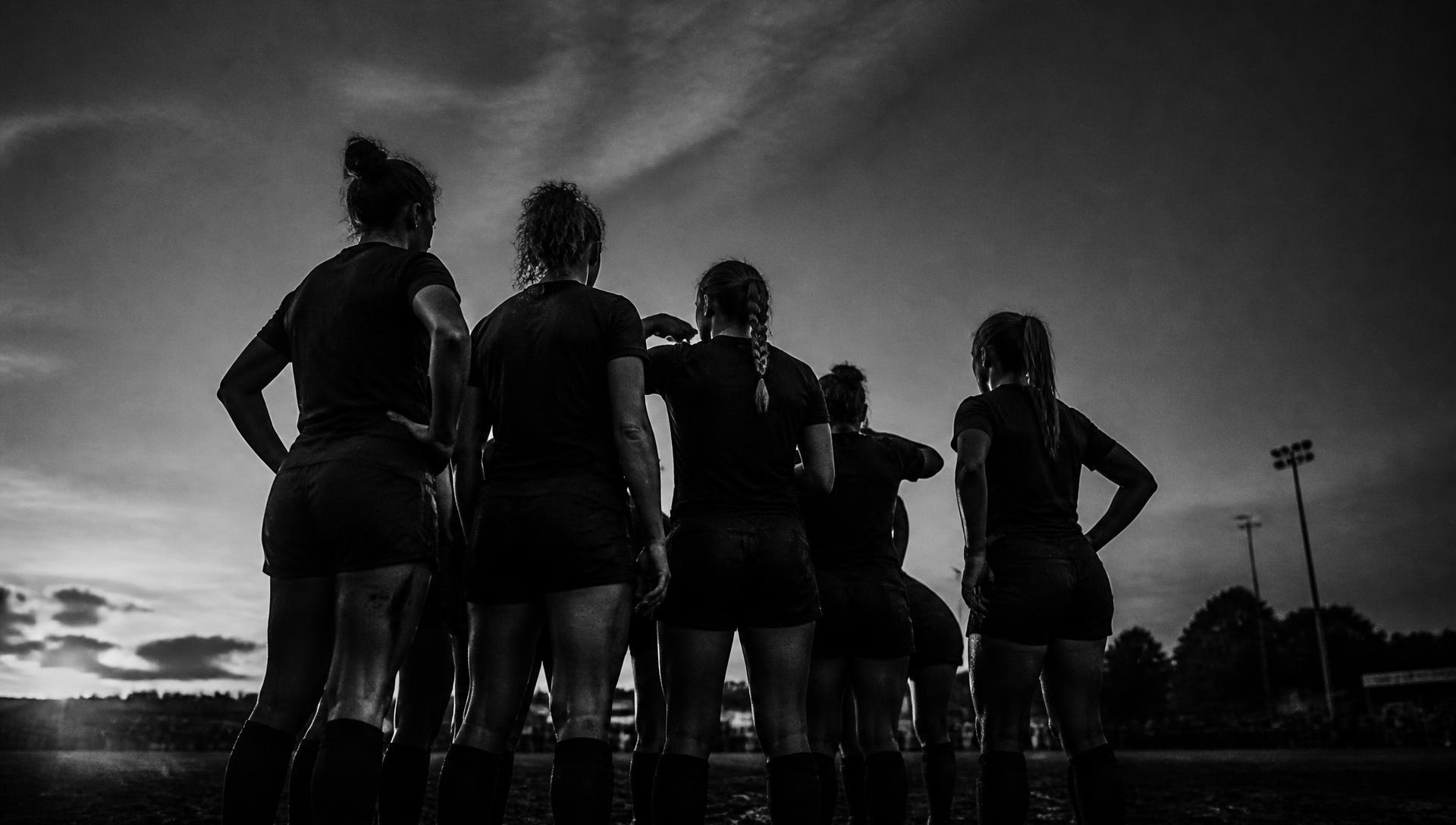 Women's team standing together on the field at dusk